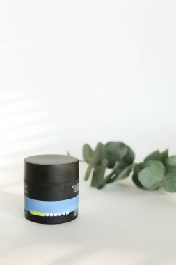 Beyaz arka planda yeşil yapraklı plastik güzellik şişesi.