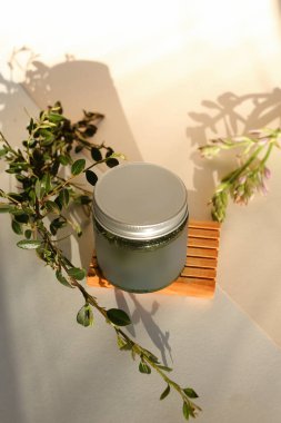 Nötr ışık arka planında izole edilmiş kremalı ve kapaklı plastik kavanoz. Güzellik merkezi ve cilt ürünleriyle ilgilenmek.
