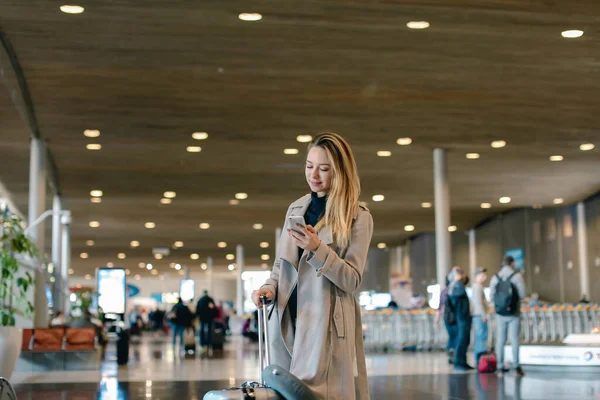 Valiz ile ayakta ve smartphone kullanarak Havaalanı salonu kız.