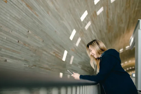 Chica rubia de pie con teléfono inteligente moderno en illumi monofónico — Foto de Stock