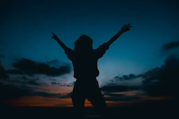 Silhouette of woman in sunset dark blue sky with clouds background. — Stock Photo, Image