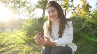 Slow Motion, arka planda gökdelenlerle mesajlaşan akıllı telefonlu, genç ve güzel Asyalı kadının yakın çekimi.