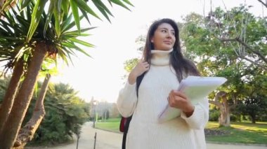 Gözlüklü neşeli bayan turist modern telefon cihazına navigatör takıyor şehir ortamında sokaklarda yürüyor. Olumlu gezgin geziniyor ve web sitesinde yeni bir yazı yayınlıyor.