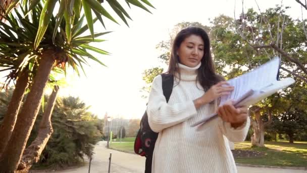 Yavaş Hareket Gözlüklü neşeli bayan turist modern telefon cihazına navigatör takıyor şehir ortamında sokaklarda yürüyor. Pozitif gezgin geziniyor ve web sitesinde yeni bir gönderi yayınlıyor. — Stok video