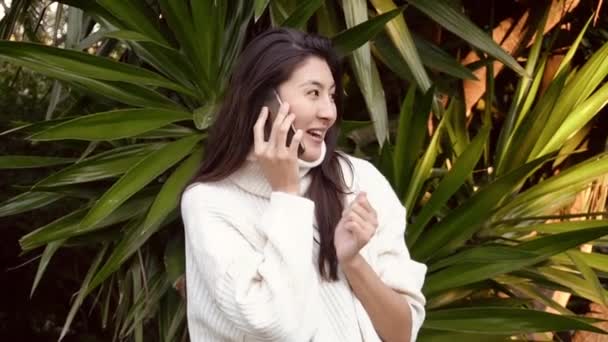 Медленное движение молодая азиатская женщина использовать телефон с наушниками во время ходьбы — стоковое видео