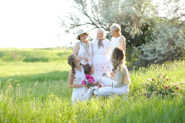 Mutlu büyükanne, kızları ve torunlarını kucaklıyor, dışarıda beyaz elbiseler giyiyor.. — Stok fotoğraf