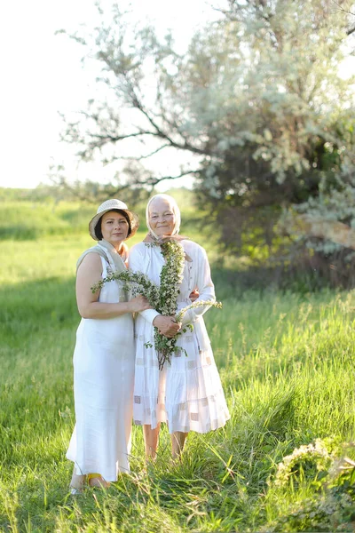 Portrait of grandmother with daughter walking in open air, wearing white dresses. — Stock Photo, Image