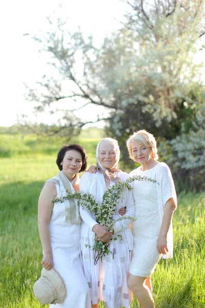 Portrait of happy grandmother with two daughters in open air, wearing white dress. — Stock Photo, Image