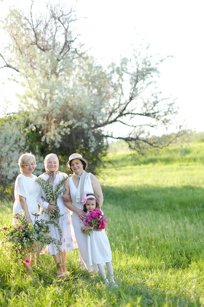 Caucasian happy grandmother in white dress with daughters and granddaughter outside. — Stock Photo, Image