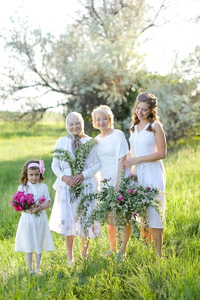 Caucasian granny in white dress with daughter and granddaughters outside. — Stock Photo, Image
