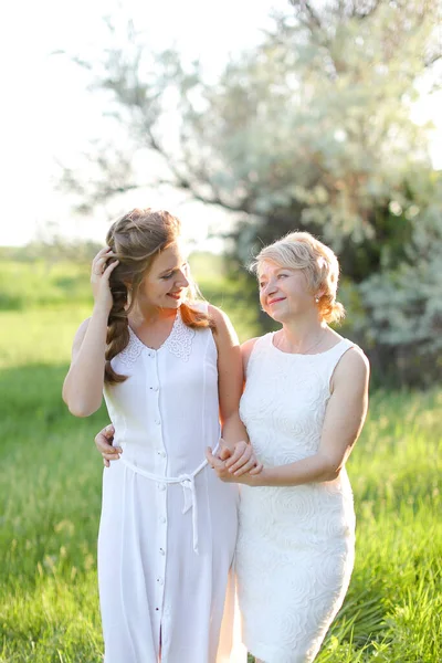 Νεαρή γυναίκα στέκεται με τη μητέρα έξω και φοράει λευκό φόρεμα. — Φωτογραφία Αρχείου