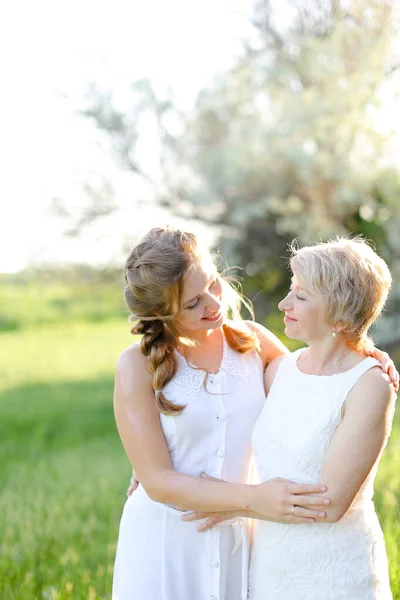 Portrait of girl standing with mother outside and wearing white dress. — Stock Photo, Image