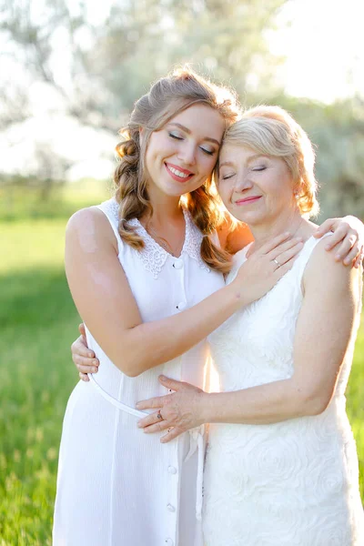 Retrato de menina abraçando mãe fora e vestindo vestido branco. — Fotografia de Stock