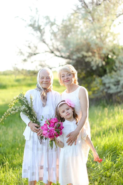 Caucasian grandmother in white dress with daughter and granddaughter outside. — Stock Photo, Image