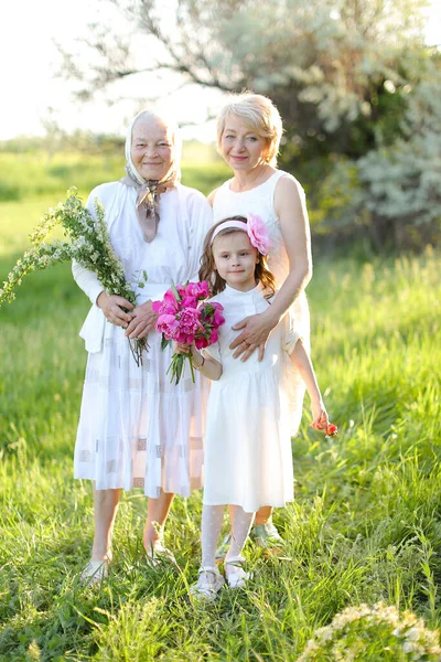 European happy grandmother in white dress with daughter and granddaughter outside. — Stock Photo, Image