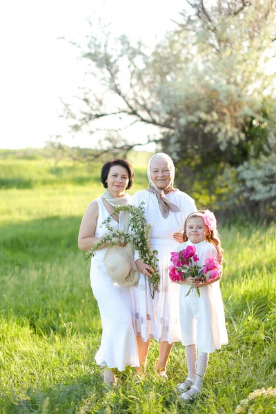 Caucasian old grandmother in white dress with daughter and granddaughter outside. — Stock Photo, Image