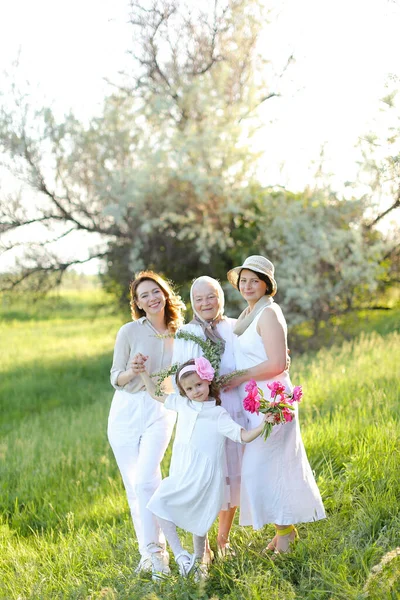 Caucasian happy granny in white dress with daughter and granddaughters outdoors. — Stock Photo, Image