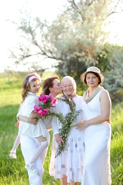 Young woman kissing granny and holding daughter outside. — Stock Photo, Image