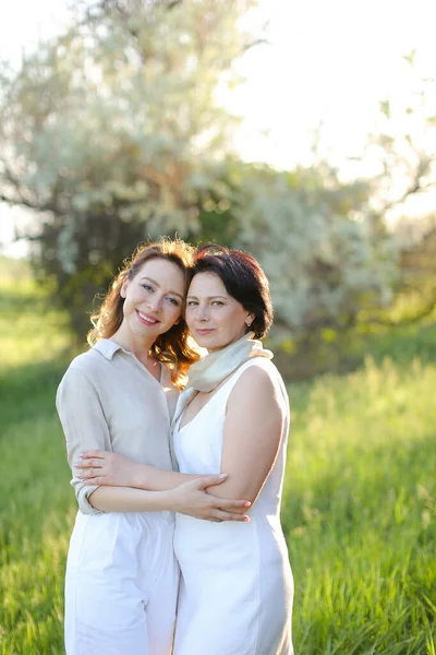 Portrait of young girl hugging mother in park and wearing white clothes. — Stock Photo, Image