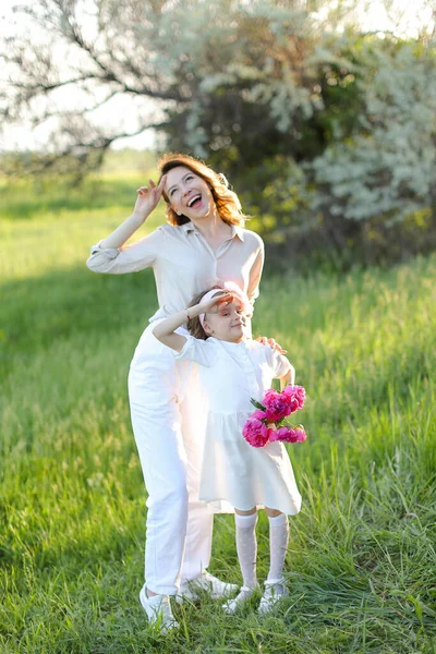 Young mother standing with little daughter on grass. — Stock Photo, Image