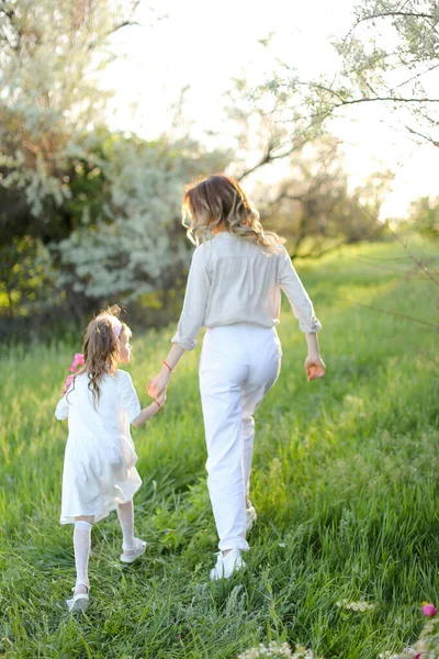 Back view of mother walking with little daughter in grass. — Stock Photo, Image