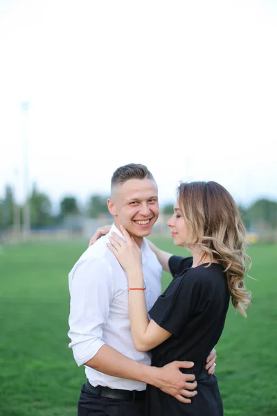 Mladý běloch muž objímající ženu na fotbalovém hřišti. — Stock fotografie