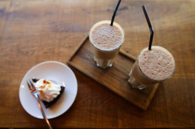 Kahve dükkanında çatallı çay tabağında pipet ve turta içen iki kahve içeceğiz..