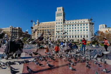 Barcelona (Katalonya, İspanya) - 6 Ocak 2022: Barcelona 'daki Plaza Catalunya' da turistler güvercinleri besliyor.