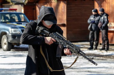 Uzhhorod, Ukrayna - 13 Şubat 2022: Genç bir adam kentin parklarından birinde siviller için düzenlenen açık bir askeri eğitim sırasında modernize edilmiş Kalaşnikof saldırı tüfeğini inceliyor.