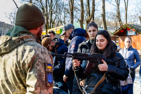 Uzhhorod, Ukrayna - 13 Şubat 2022: Bir askeri eğitmen, şehir parkındaki açık bir eğitim sırasında sivillere modern Kalaşnikof saldırı tüfeği tutmayı öğretiyor.