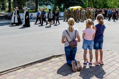 Velykyi Bereznyi, Ukrayna - 11 Mayıs 2022: Çocuklu bir anne, Rus saldırganla savaşta ölen Ukraynalı bir askerin cenaze töreninin önünde diz çöktü.
