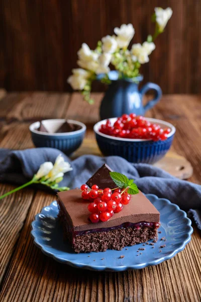 Sweet cocoa dessert with red currant filling, topped with chocolate mousse and fresh berries