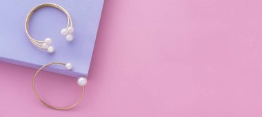 Kağıt üzerinde inci bilezikli iki altının panoramik çekimi. Renk arkaplanı ve fotokopi alanı