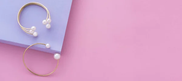 Plano panorámico de dos de oro con pulseras de perlas sobre papel pastel de color de fondo con espacio de copia —  Fotos de Stock