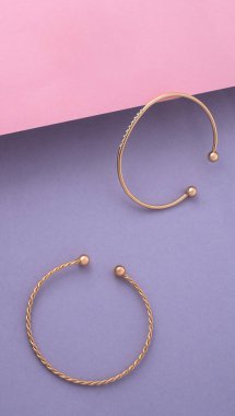 Vertical high angel shot of two modern bracelets on pink and purple background with copy space
