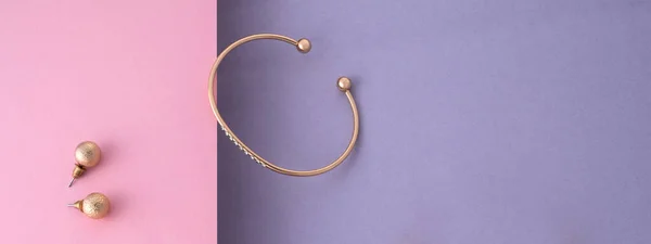 Panoramic shot of golden with diamonds bracelet and earrings pair on pink and purple with copy space — Zdjęcie stockowe