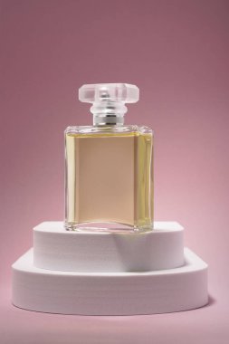 Beyaz podyumdaki lüks parfüm şişesi. Pembe arka planda. Kopya alanı da var.
