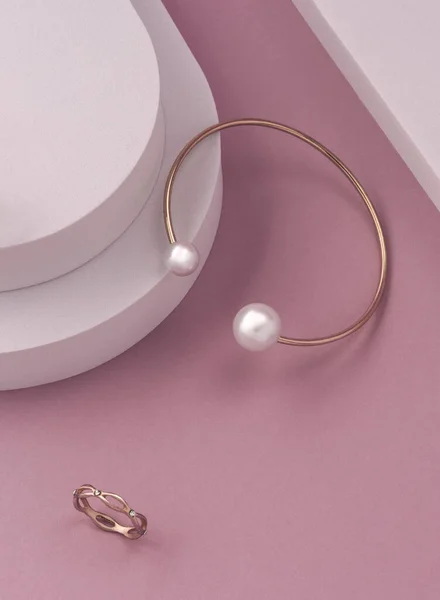 Вид сверху на современный золотой и персиковый браслет и кольцо на розовом и белом фоне с копировальным пространством — стоковое фото