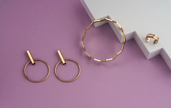 Zigzag forma pulsera de oro y pendientes modernos par sobre fondo geométrico blanco y rosa con espacio de copia —  Fotos de Stock