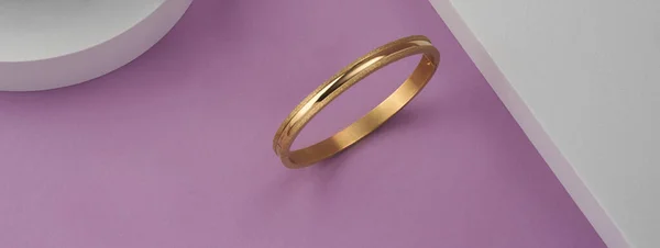 Panorama nowoczesnej złotej bransoletki na różowo-białym tle z przestrzenią do kopiowania — Zdjęcie stockowe