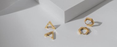 Üçgen ve altıgen panoraması, beyaz zemin üzerinde fotokopi alanı olan modern altın küpeleri şekillendirir.