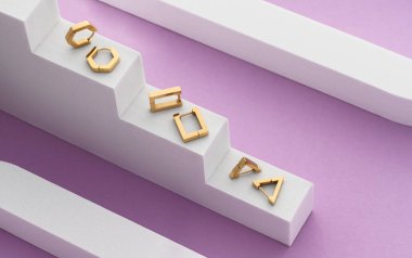 Üç çift geometrik tasarımın üst görüntüsü altın küpeler üzerinde beyaz podyum üzerinde mor zemin üzerinde kopya alanı ile