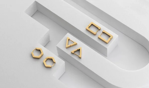 Widok z góry nowoczesnych geometrycznych złotych kolczyków na geometrycznym białym tle — Zdjęcie stockowe