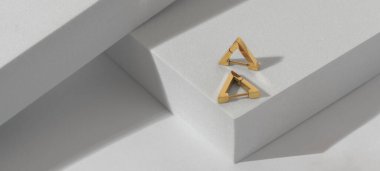 Geometrik beyaz arkaplandaki altın küpelerin panoramik görüntüsü