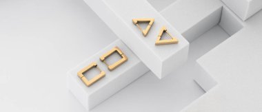 Beyaz arkaplanda, kopyalama alanı olan altın geometrik küpelerin üst görünümü