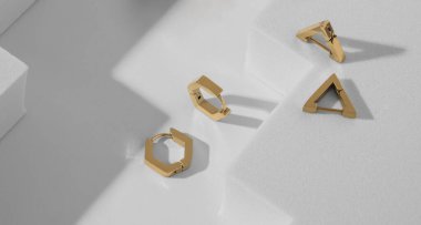 Beyaz arkaplanda metin boşluğu olan geometrik şekilli altın küpeler