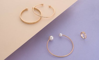 İnci ve elmaslar altın bilezikler ve bej ve mor arkaplan üzerinde yüzükler kopya alanı ile