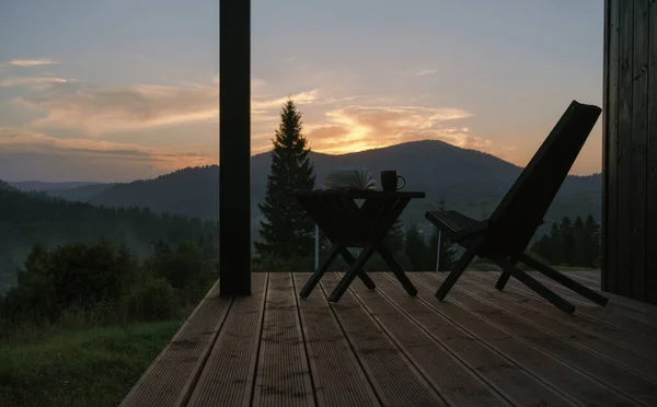 Modern chair and table on terrace with mountain view at sunset with copy space