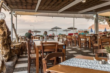 Platanias, Girit, Yunanistan, 7 Ekim 2021 Deniz manzaralı bir Yunan restoranında bir masada oturan erkek ve kadın.