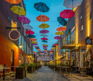 Danimarka 'nın başkenti Vejle' deki Latin Mahallesi 'nde bir caddenin üzerindeki yumuşak akşam ışığında renkli şemsiyeler, 14 Haziran 2022